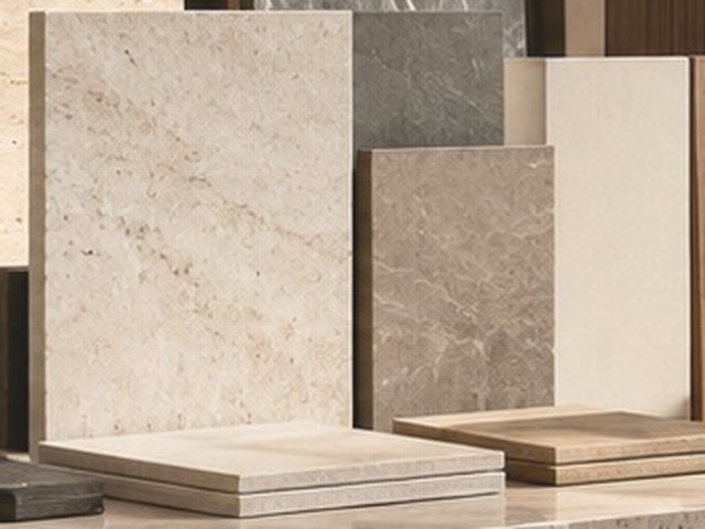 Square tile samples in cream and grey tones on a travertine bench